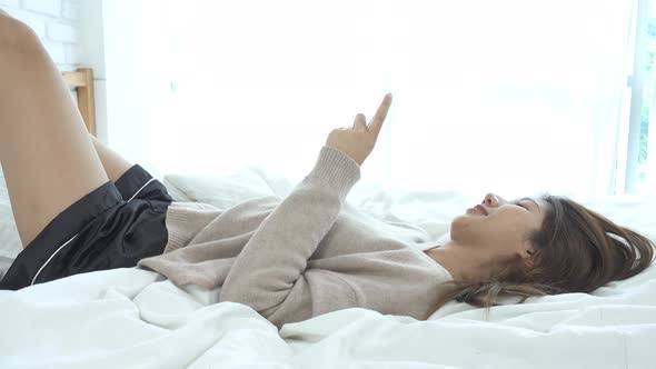 Asian women are using smart phone on the bed in morning. Asian woman in bed checking social apps
