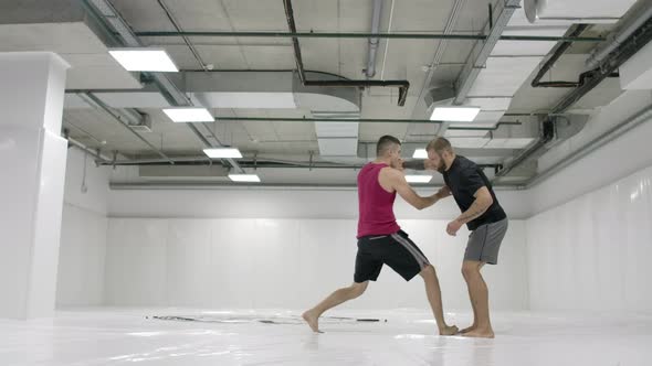 Two Male Wrestlers in a White Room Work Out Throwing Mats