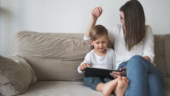 Family Mother and Child Using Tablet Sitting on Sofa at Home