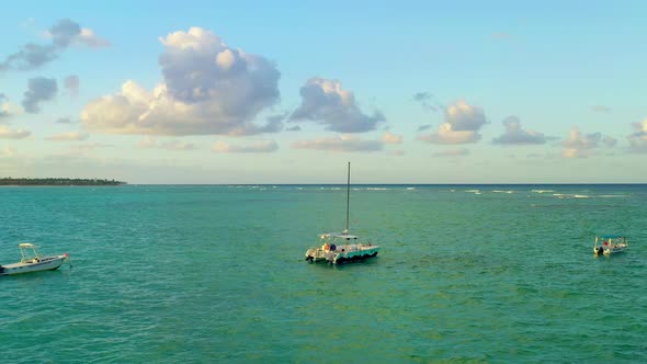 Scenic flyover catamaran boat moored in green ocean sea waters, overhead aerial approach