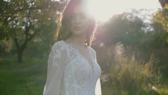 Young beautiful brunette woman in white dress enjoying her life, turning around, throwing her hair i