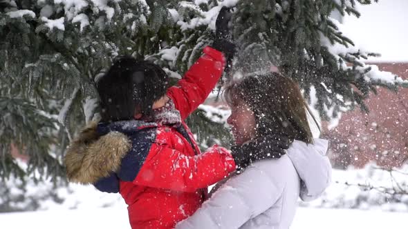 Asian Mother And Son Enjoying Snowy Winter Day Outdoors