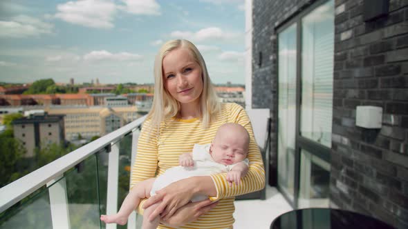 Portrait Shot of Mother Carrying Sleeping Baby in the Balcony on a Beautiful Sunny Day