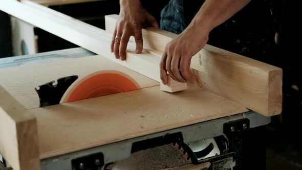 A carpenter processes a wooden blank on a circular saw in a carpentry workshop. Craftsmanship