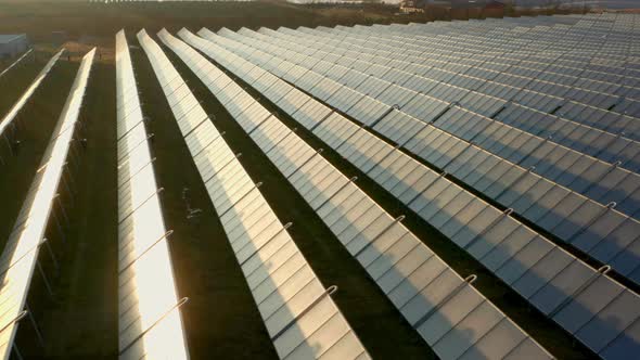 Drone Over Sunlit Rows Of Solar Panels In Field At Sunset