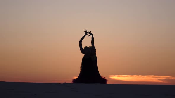 Dancer Dances on the Sand Against the Background of a Fiery Sunset. Silhouettes