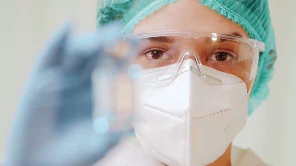 Female Doctor Holds an Ampoule of Coronavirus Vaccine in Her Hands.