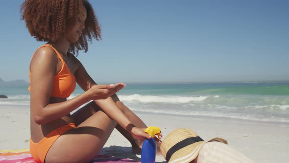 African American woman applying sunscreen at beach