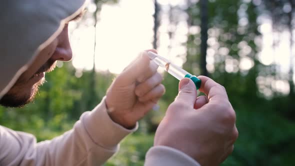 A Male Biologist Examines a Forest Mushroom in a Test Tube