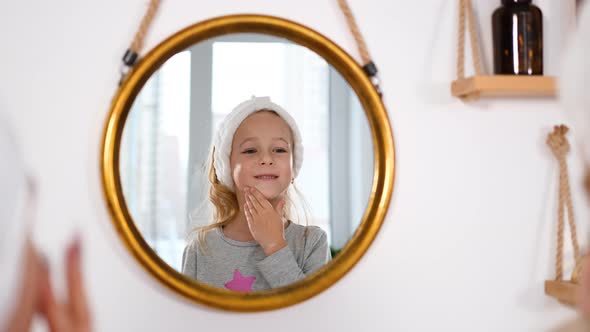 Little Girl Applying Creme on Face in Bathroom