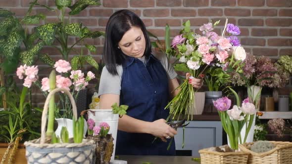 Professional florist cuts off stems of roses with cutters in store