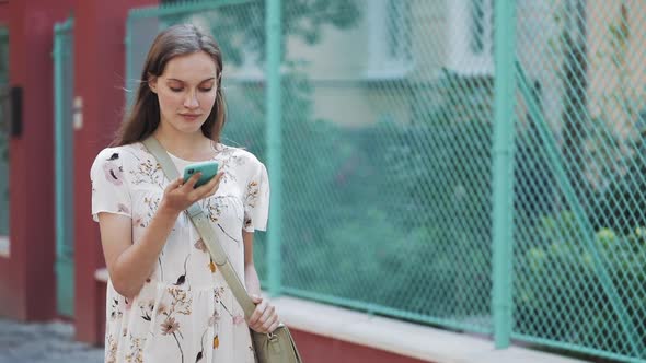 Pretty Woman Wearing White Flower Dress with Bag Cross Her Shoulder Using Her Smartphone Voice
