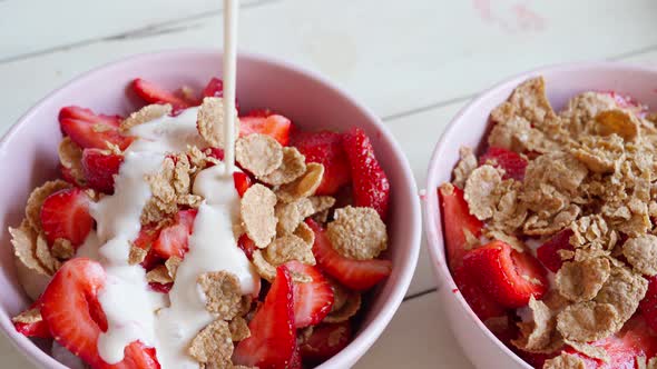 Pouring Yogurt Into Bowl Full of Cutted Strawberry and Flakes