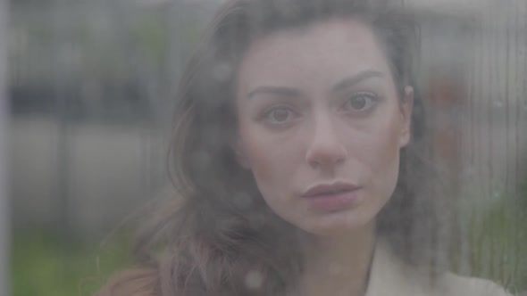 Portrait of Young Beautiful Caucasian Woman Looking at Camera Through Window. Face of Charming Lady