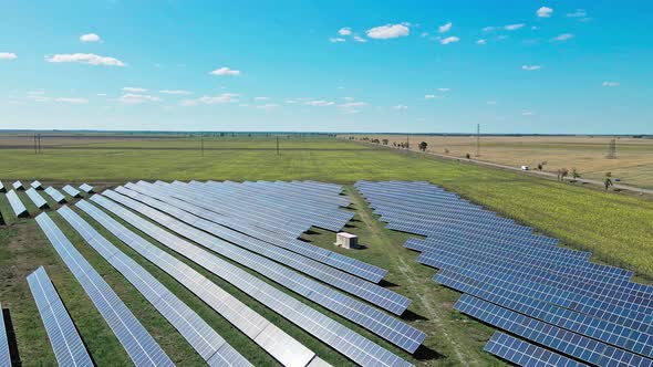 Aerial View of Solar Panels Farm on Green Field Under Blue Sky