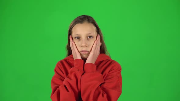 Little Female Is Scared and Hiding Her Face in Studio on Green Background