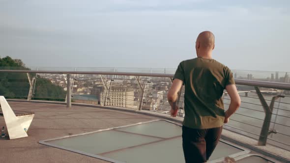 Young Man in Sports Uniform Runs on the Pedestrian Bridge at Dawn