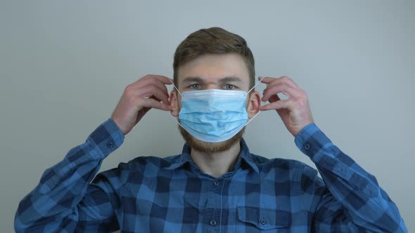 Man putting on medical face mask for virus infection prevention and protection.
