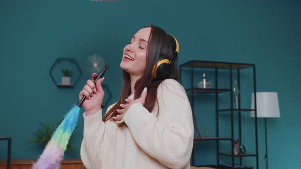 Young Dancing Woman Dusting Furniture Alone Caring for Hygiene Using Colorful Duster in Room at Home