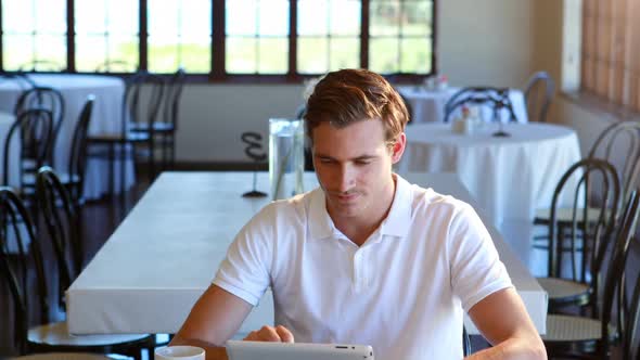 Man having cup of coffee and using digital tablet