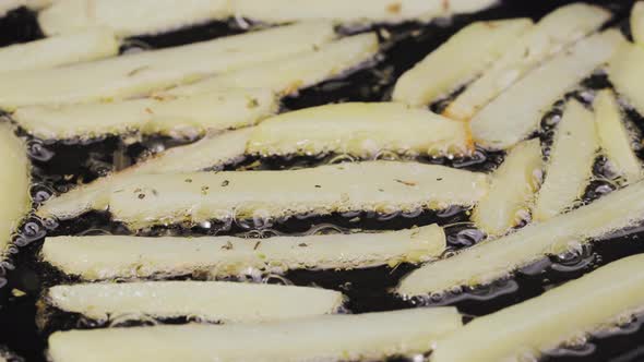 Frying Potato Strips Into a Hot Pan with Oilin and Seasoning Close Up