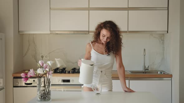 The Woman is Taking a Kettle of Hot Water and Pouring Tea