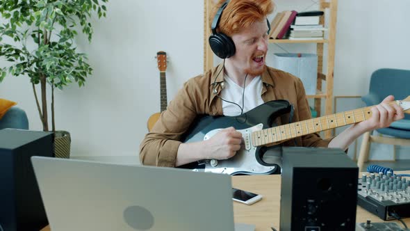 Slow Motion of Attractive Young Musician Playing Guitar and Singing Having Fun in Apartment