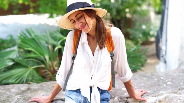 Beautiful Joyful Tourist Woman in Straw Hat and White Shirt Looking and Smiling at Camera