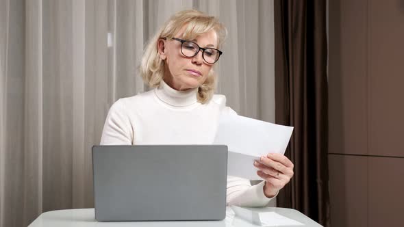 Mature Woman Opens Envelope Writes and Counts Utility Bills