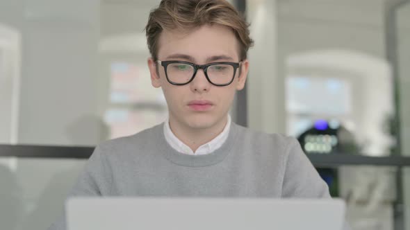 Close Up of Young Man with Laptop Smiling at the Camera