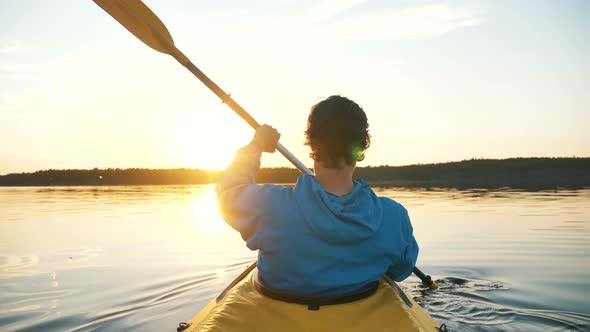 Sportsman Rowing a Kayak on the Calm Surface of the Water at Sunset, Outdoor Activities