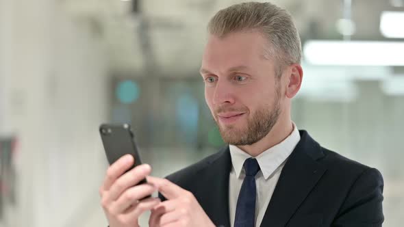 Portrait of Excited Young Businessman Celebrating Success on Smartphone