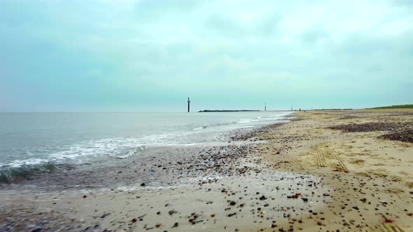 Cinematic low flying aerial drone shot over sand and sea on a beach, UK