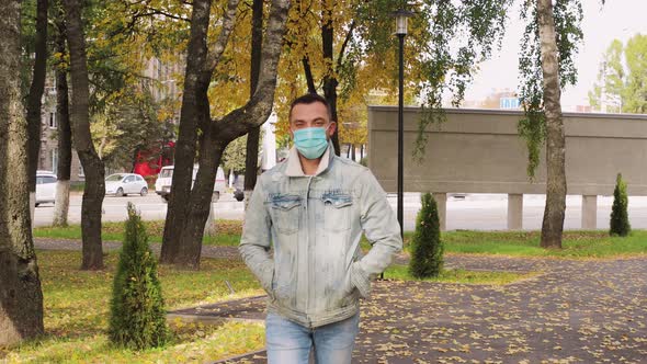 A Young Man in a Medical Mask is Walking at Us While Looking at the Camera