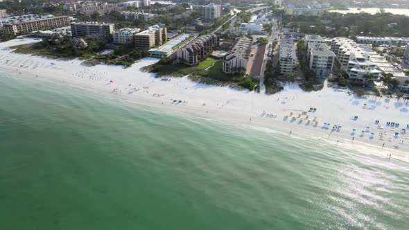 The camera rotates around a white sandy beach showing the waves crashing on the beach. Small beach h