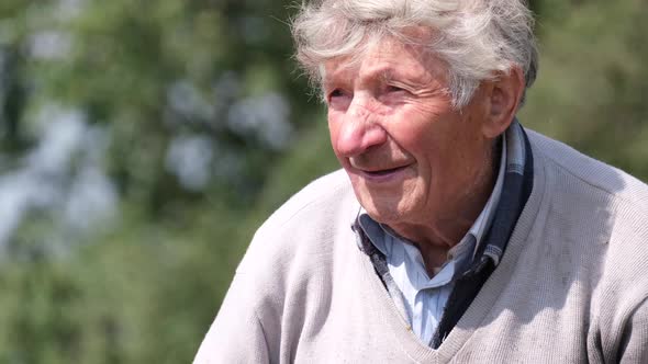 Old Grayhaired Grandfather with Curly Hair Looks at the Camera