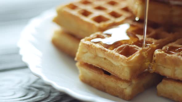 Honey pouring on a fresh waffles. Breakfast with Belgian waffles