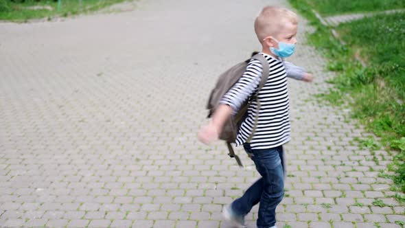 Blonde Boy Playing on Street Spinning with Backpacks After School Child Wearing Mask Safety