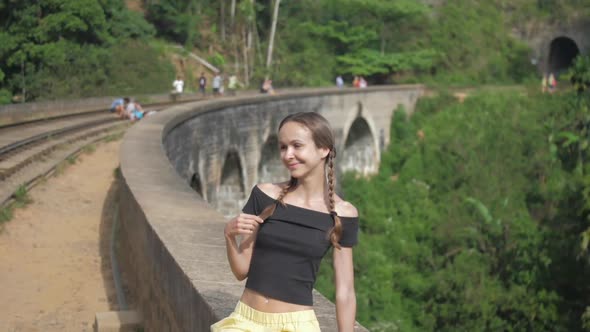 Girl in Open Top Poses on Old Bridge Smiling Against Forest