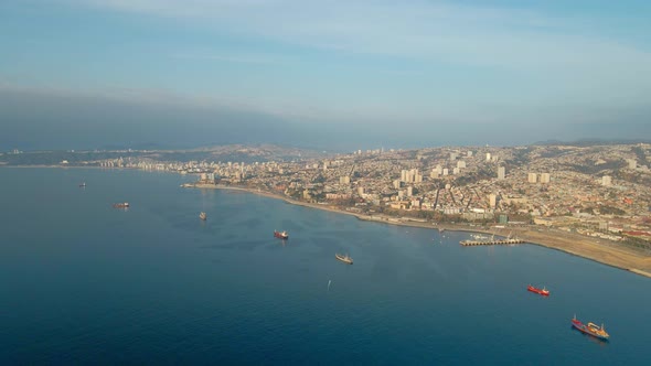 Aerial dolly in of Valparaiso picturesque hillside city and cargo ships sailing in sea near the coas