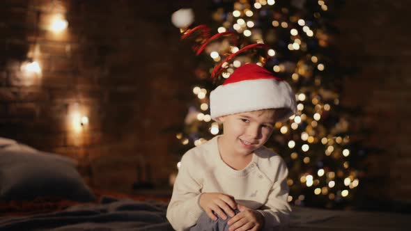 Little Boy Dressed Santa Hat and Shakes His Head