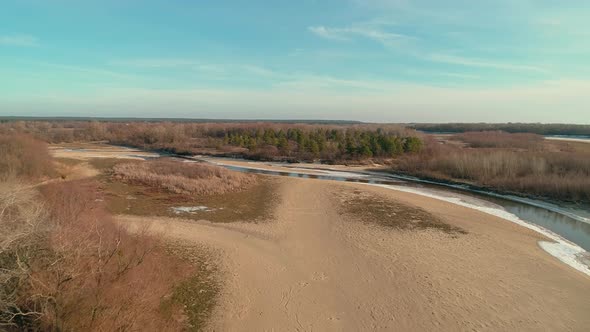 Aerial Drone Footage of Flight Over a Sandy Shore with a Small River in Winter