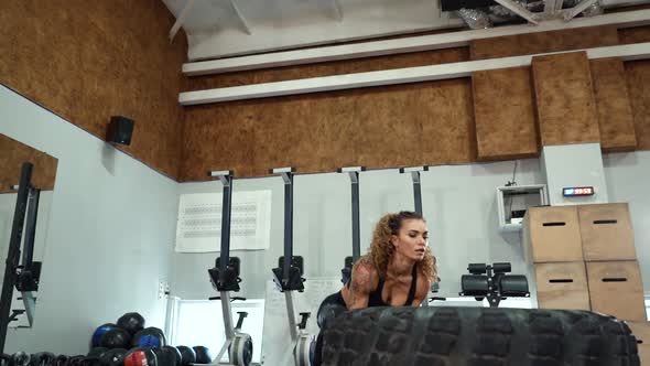 Fit female athlete working out with a huge tire