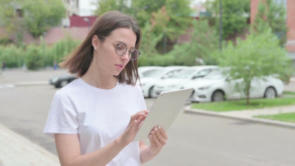 Young Woman Browsing Internet on Tablet while Walking on Street