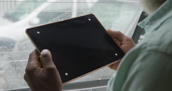 Video of african american senior man using tablet with black screen