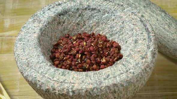 Dried szechuan or sichuan pepper in a stone mortar close up  