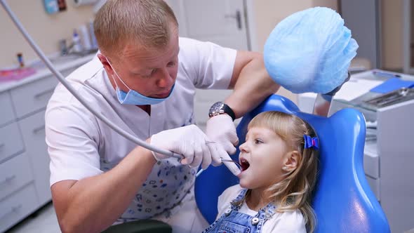 Stomatologist with little girl. Male dentist treating child's teeth at dentist office.