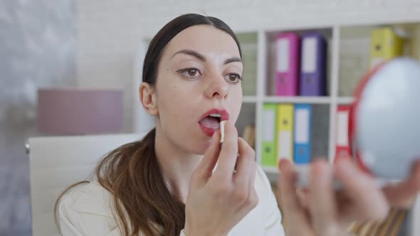 Stylish Gorgeous Millennial Businesswoman Applying Lipstick in Slow Motion Looking at Hand Mirror