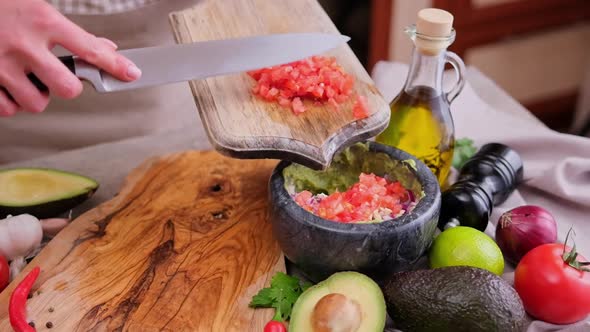 Making Guacamole Sauce  Woman Pouring Chopped Onion Into Bowl with Mashed Avocado and Onion