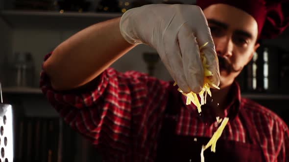 A Young Moustache Cook is Sprinkling Grated Cheese in Process of Preparing Meal in Slow Motion